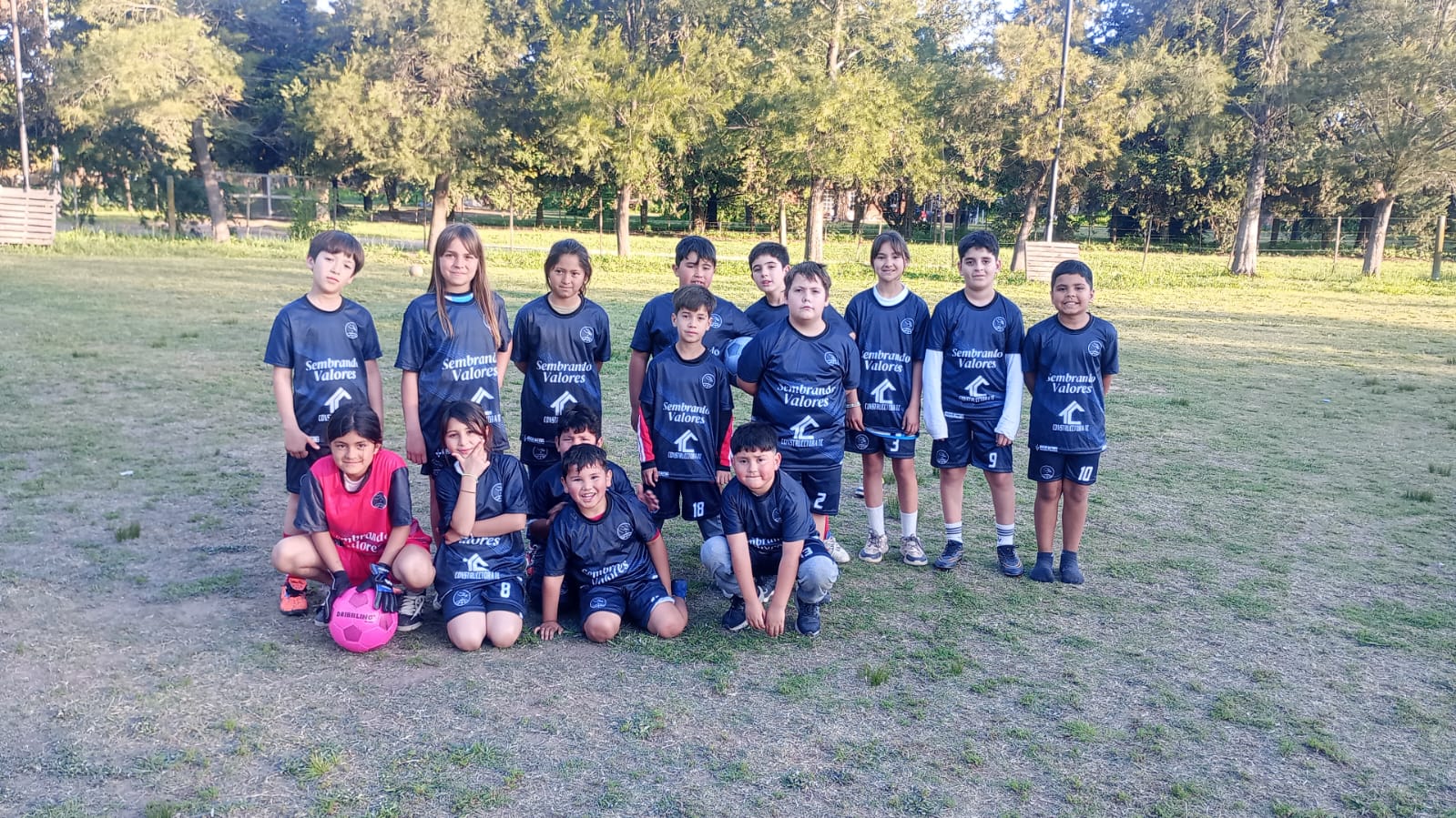 Equipo de la escuela de fútbol posando en la cancha con la camiseta de Sembrando Valores